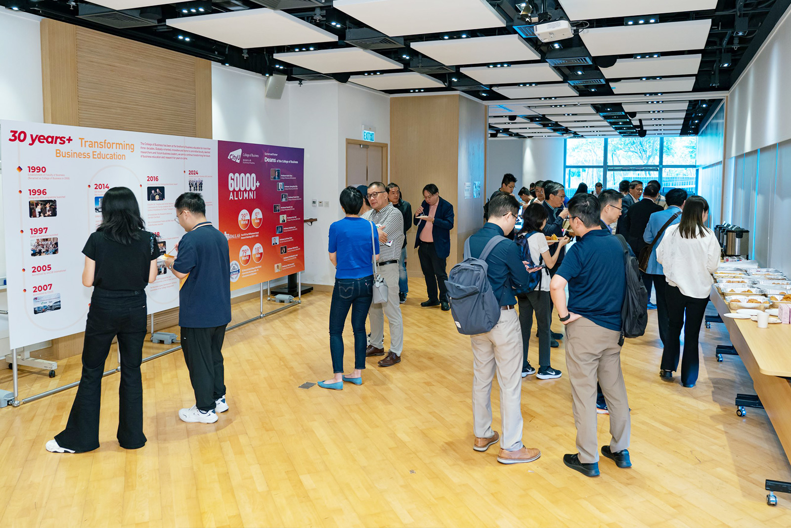 Alumni enjoy the refreshments and networking session before the exhibition board showcasing the College's journey and milestones.